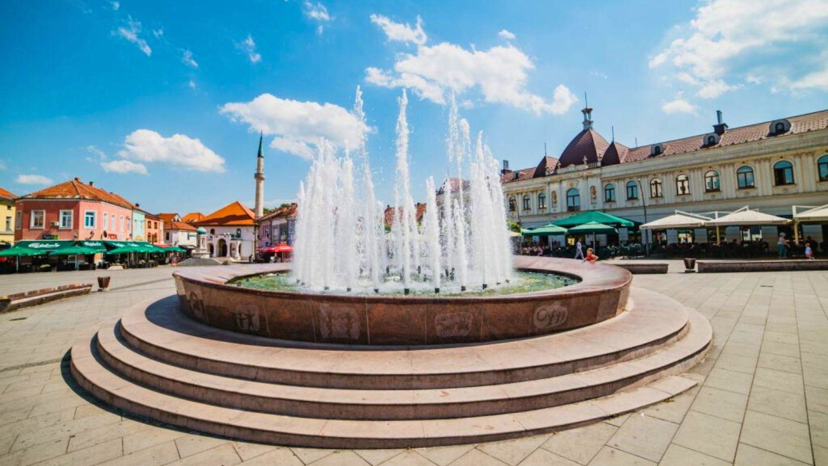 The fountain on Freedom Square on a summer day, café umbrellas behind it