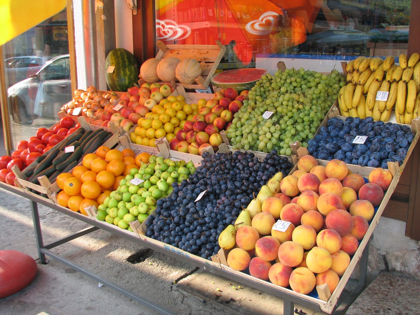 A market stall full of peaches, plums, grapes and bananas