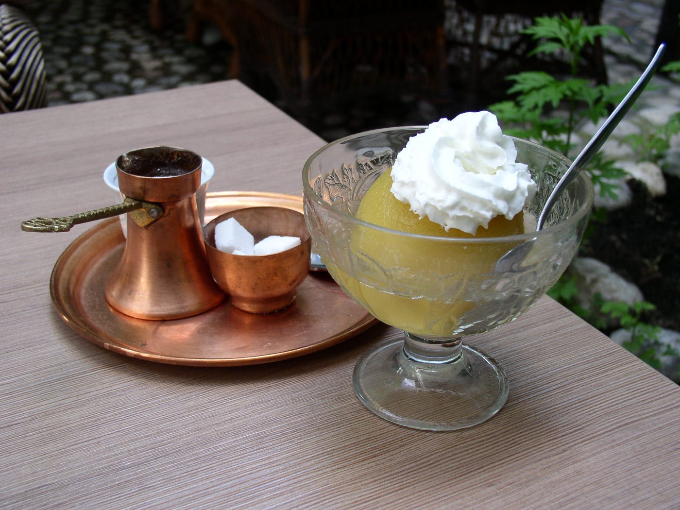 Tufahija, a poached apple with whipped cream, beside a copper coffee set